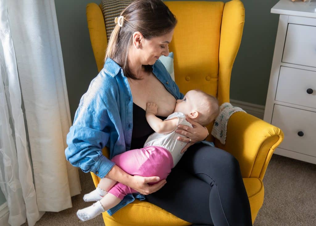 mother breastfeeding and smiling at baby