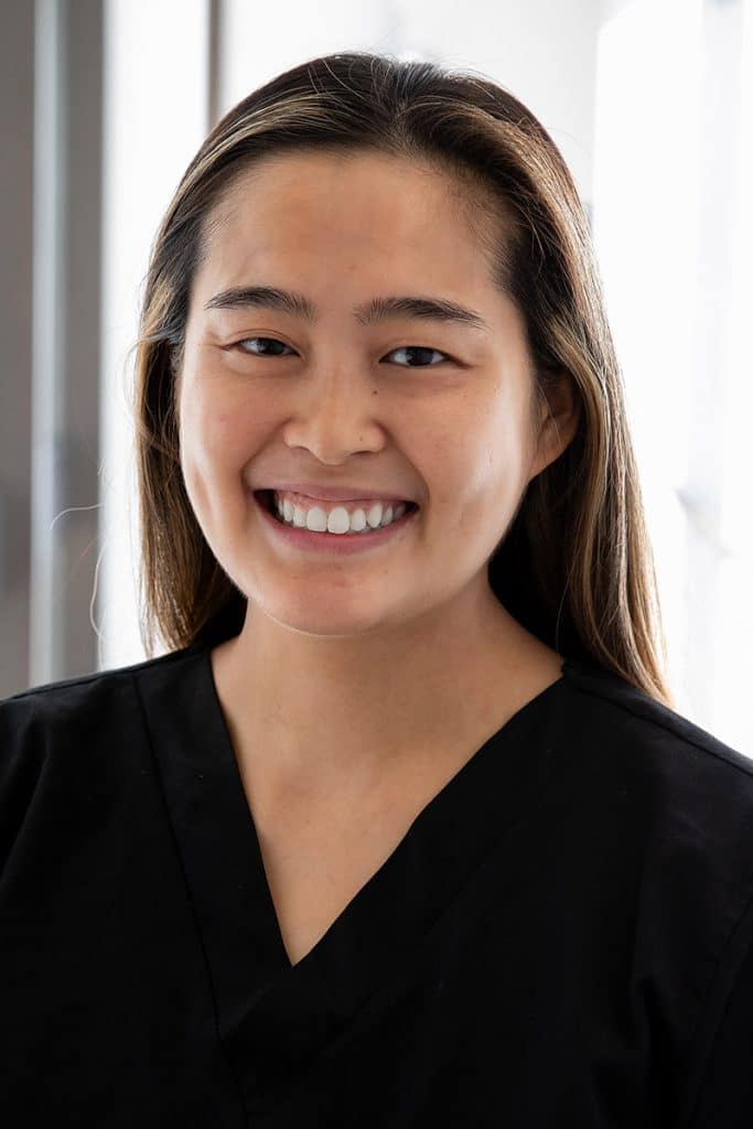 Vivian Lai smiles in a professional headshot, wearing black scrubs